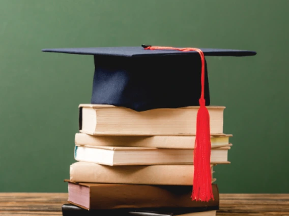 A Stacks of books and a graduate cap