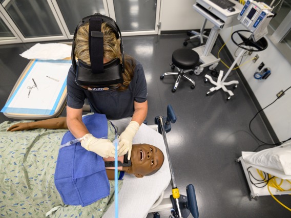 A student wearing a headset and performing a medical simulation.