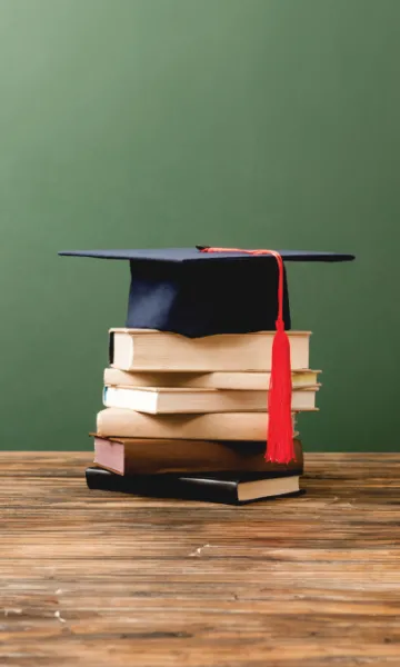 A Stacks of books and a graduate cap