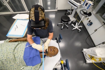 A student wearing a headset and performing a medical simulation.